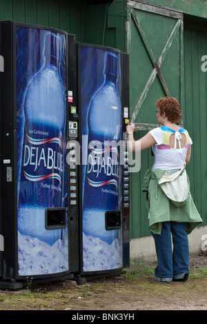 Deux distributeurs automatiques Deja Blue d'eau en bouteille purifiée boissons gazeuses dans la rue de la ville avec femme personne en plein air en dehors vertical USA US haute résolution Banque D'Images