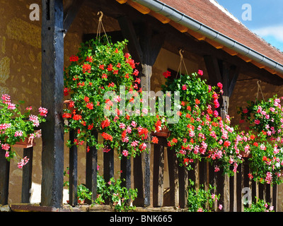 Paniers suspendus et des jardinières sur le balcon en bois de la maison en pierre - France. Banque D'Images