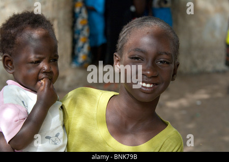 Afrique, Sénégal, Dakar. Village Wolof, le plus grand groupe ethnique du Sénégal, principalement les agriculteurs et pêcheurs. Jeune fille avec bébé. Banque D'Images