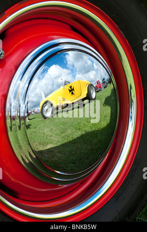 Reflet d'une croix de fer allemande ford hot rod voiture dans un chapeau de moyeu de roue chrome à un american car show. UK Banque D'Images