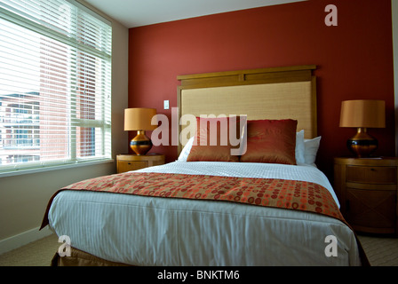 Chambre d'éclairage naturel lit double affichage avec des coussins décoratifs tables et lampes de chevet Banque D'Images