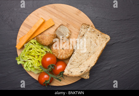 Le déjeuner traditionnel anglais Plowmans de fromage, pain, tomate, laitue et pork pie sur plateau en bois. Banque D'Images