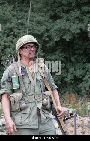 Une reconstitution de la conflit du Vietnam. Un soldat vêtu de l'uniforme militaire complet portant un canon de radio, à ses côtés. Banque D'Images