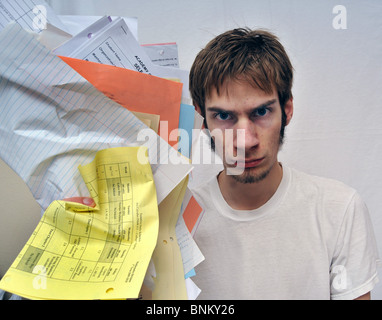 Un jeune homme surchargé par le travail scolaire, les devoirs, et de paperasse. Banque D'Images