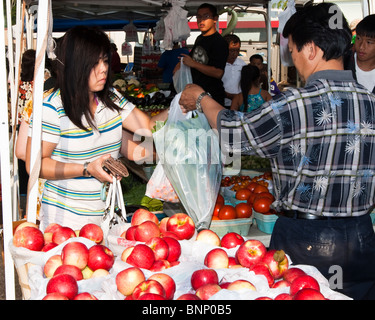 Une femme achète des légumes frais à un marché de producteurs au centre-ville de Saint Paul. Banque D'Images