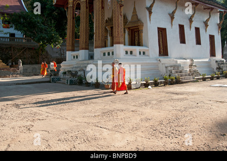 Les moines bouddhistes se promener dans les jardins du temple à Luang Prabang au Laos Banque D'Images