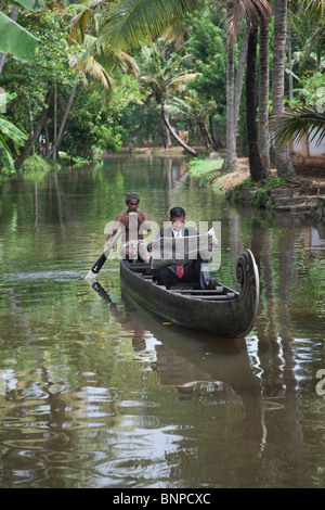 Jeune homme d'affaires indien dans un costume noir avec chemise blanche et cravate rouge lire le journal sur son chemin à l'office dans un woode Banque D'Images