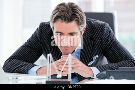 Confiant mature businessman looking at boules cinétiques Banque D'Images