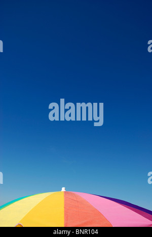 De couleur arc-en-ciel parasol à la plage contre le ciel bleu clair. Banque D'Images