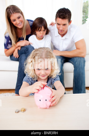 Adorable petite fille l'insertion d'une pièce de monnaie pour une tirelire Banque D'Images