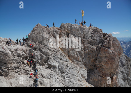 Les touristes à la croix d'Or - le point le plus élevé en Allemagne sur le sommet du mont Zugspitze à 2,962m au-dessus du niveau de la mer - sur un jour d'été ensoleillé Banque D'Images