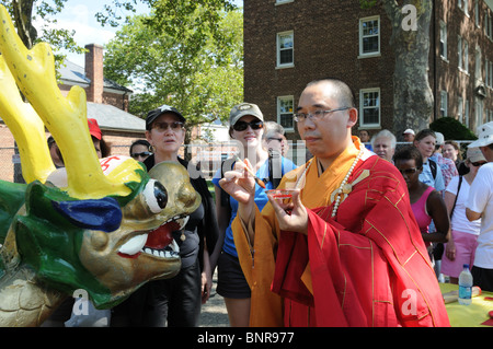 Un moine bouddhiste en peinture d'un point rouge sur l'oeil du dragon de proue d'un bateau qui participera à un Dragon Boat Festival. Banque D'Images
