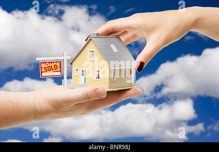 Pour atteindre une maison avec vendu enseigne immobilière sur un fond de ciel nuageux bleu vif. Banque D'Images