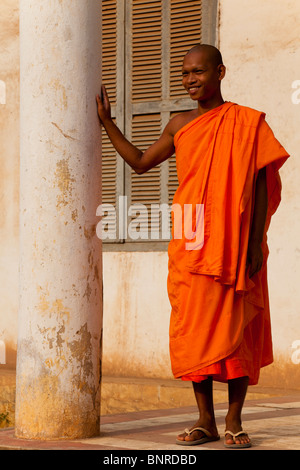 Moine novice cambodgienne en robe safran appuyé contre une colonne - Province de Kandal, Cambodge Banque D'Images