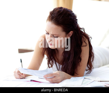 Femme concentré notes in bed Banque D'Images