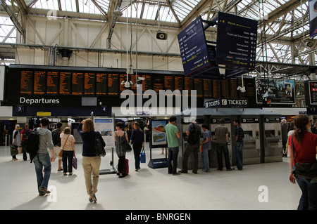 Les clients utilisant des distributeurs de billets et les trains en partance de sélection dans le grand hall de la gare Waterloo à Londres UK Banque D'Images