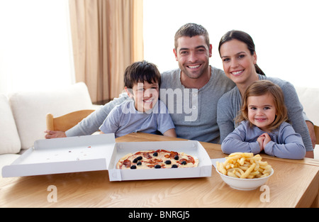 Family eating pizza et frites à la maison Banque D'Images