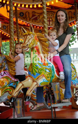 Mère et enfants assis sur un champ de foire ride Banque D'Images