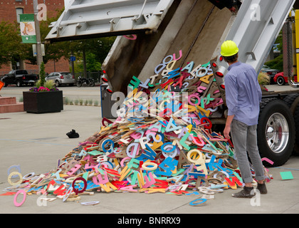 Un dump truck dumping out un tas de découper des lettres sur le ciment. Banque D'Images