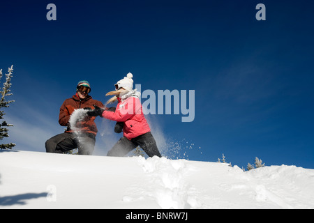 Un homme et une femme jouent dans la neige dans les montagnes. Banque D'Images