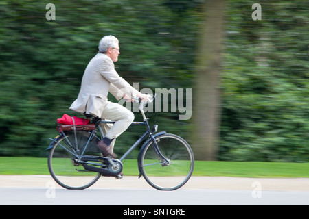 Homme en costume de rouler à vélo dans un parc Banque D'Images