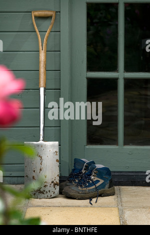 Bottes et bêche à l'extérieur d'un bâtiment de jardin Banque D'Images