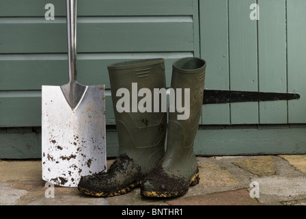 Spade et les bottes par un abri de jardin. Banque D'Images