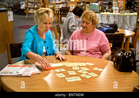 Un instructeur bénévole lecture lecture enseigne à une vieille femme hispanique dans une bibliothèque publique à Lake Forest, en Californie. Banque D'Images