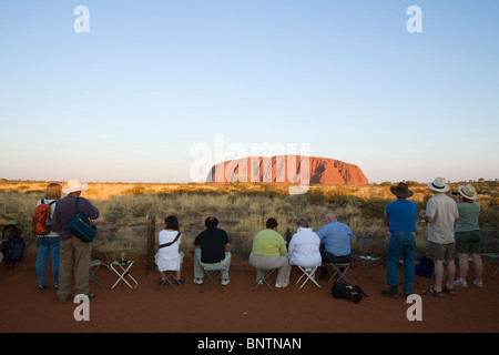 Les touristes se rassemblent pour regarder le coucher du soleil sur Uluru (Ayers Rock). Le Parc National d'Uluru-Kata Tjuta, Territoire du Nord, Australie. Banque D'Images