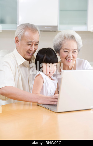 Petite fille à l'aide d'un ordinateur portable avec ses grands-parents Banque D'Images