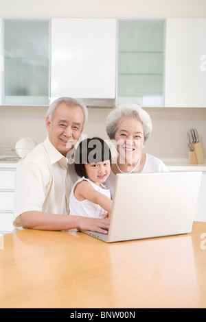 Petite fille à l'aide d'un ordinateur portable avec ses grands-parents Banque D'Images