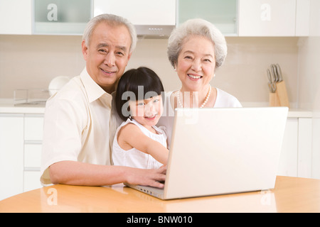 Petite fille à l'aide d'un ordinateur portable avec ses grands-parents Banque D'Images