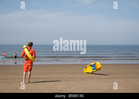 Un sauveteur RNLI patrouillant la plage à Scarborough, Yorkshire du Nord. Banque D'Images