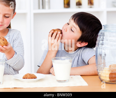 Sœur sourire manger des biscuits et boire du lait Banque D'Images