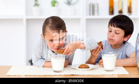 Happy brother and sister manger des biscuits et boire du lait Banque D'Images