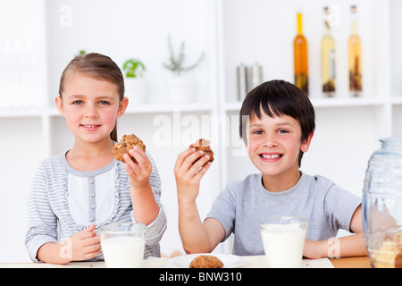 Smiling brother and sister manger des biscuits et boire du lait Banque D'Images