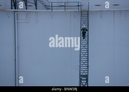 Travailleur descendant des escaliers sur un réservoir d'huile Banque D'Images