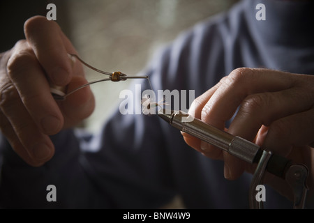 Mains travaillant sur fly fishing hook Banque D'Images