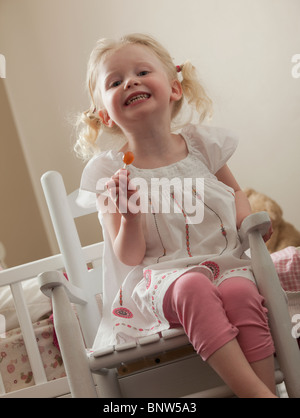 Jeune fille dans un fauteuil à bascule de manger une bonne poire Banque D'Images