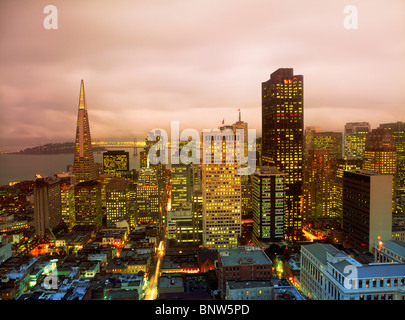 Bâtiment à usage de lumières avec Transamerica Pyramid et Oakland Bay Bridge à San Francisco skyline at Dusk Banque D'Images