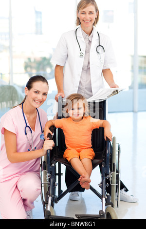 Petite fille dans un fauteuil roulant médecins regardant la caméra Banque D'Images