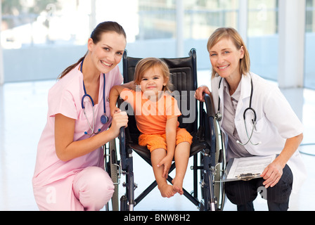 Bébé dans un fauteuil roulant avec l'infirmière et un médecin Banque D'Images