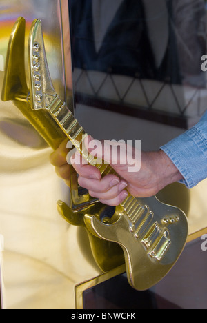 La main de l'homme à la guitare à l'entrée de la poignée de porte en forme de Hard Rock Cafe sur le fleuve à pied à San Antonio, Texas, USA Banque D'Images