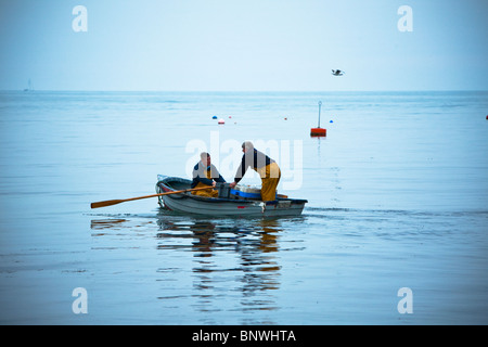 Aviron les pêcheurs à leur bateau de pêche tôt le matin, Swanage, Dorset, UK Banque D'Images