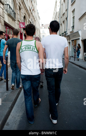 Jeune adulte, gay couple masculin , Walking away, Down Street dans le quartier du Marais, quartier gay de Paris tenant la main, Paris, France, été, couples de diversité Banque D'Images