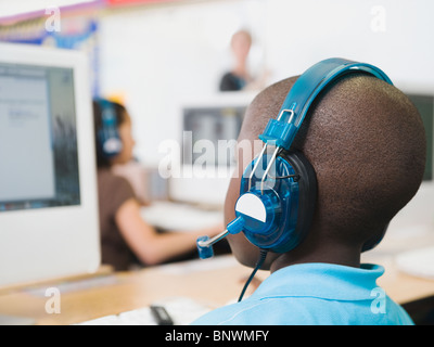 Élève d'école élémentaire portant des écouteurs in classroom Banque D'Images