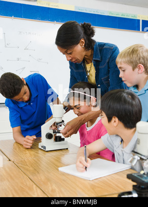 Aider les élèves enseignants utiliser microscope in science lab Banque D'Images