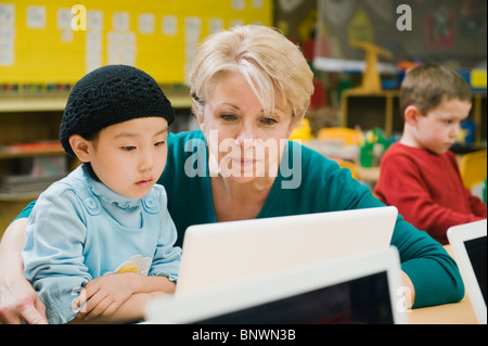 Professeur et élève de maternelle looking at laptop Banque D'Images