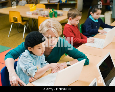 Professeur et élève de maternelle looking at laptop Banque D'Images