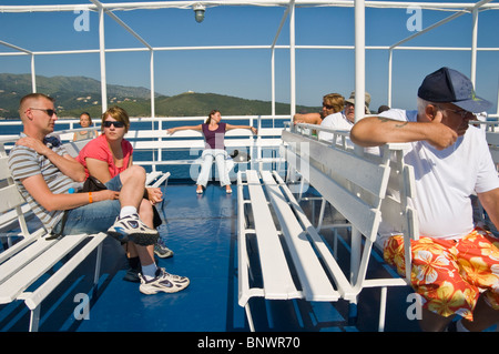 Les touristes se détendre sur le pont du ferry au large de l'île grecque de Corfou Grèce GR Banque D'Images